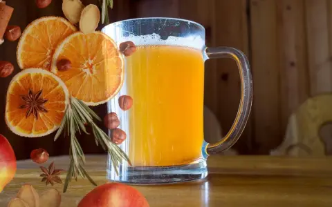 Szklanka piwnego grzańca z pomarańczą, anyżem, orzechami i rozmarynem.
