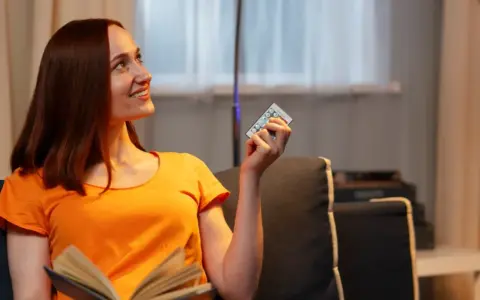 Mujer sonríe con un control remoto en mano, pensando que 800 kWh es mucho para su factura de luz.