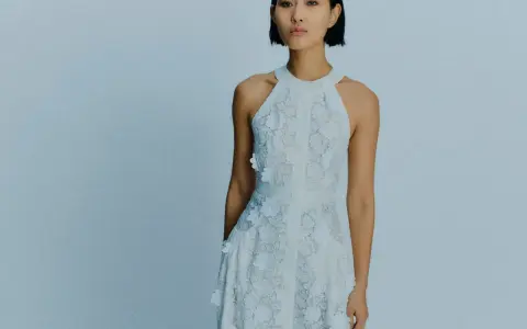 Ein Model trägt ein weißes Spitzenkleid mit Blumenapplikationen. Welche Farbe passt zu Himmelblau? Dieses Kleid ist eine zarte Antwort.