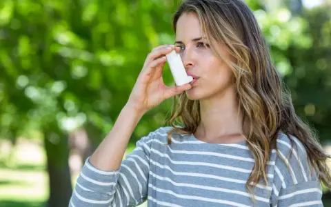 Frau mit Inhalator im Freien. Bei Asthma kann die richtige Dosierung von Prednisolon Tabletten wichtig sein.