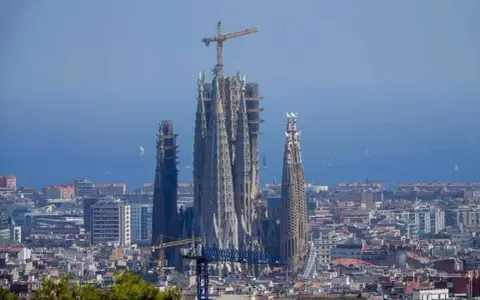 La Sagrada Familia, en plein temps de construction, domine le paysage urbain de Barcelone. Des grues témoignent de l'évolution de ce chef-d'œuvre architectural.