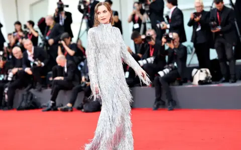 Isabelle Huppert, éblouissante dans sa robe argentée à franges, foule le tapis rouge de la mostra de Venise, sous le regard des photographes.