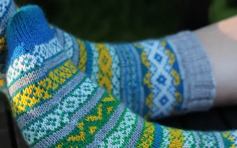 Två par stickade sockor med färgglatt sticka mönster med två färger i blått, gult, grönt och vitt.