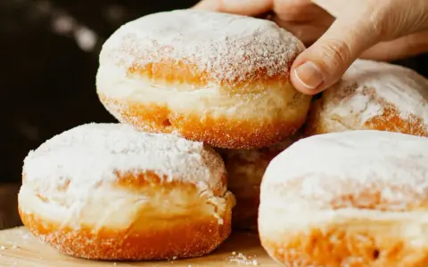 Stos puszystych pączków oprószonych cukrem pudrem. Idealne na tłusty czwartek, te fit pączki kuszą apetycznym wyglądem.