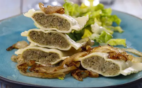 Gestapelte Maultaschen mit gebratenen Zwiebeln und Salat. Ein köstliches Maultaschen Rezept, das Appetit macht.