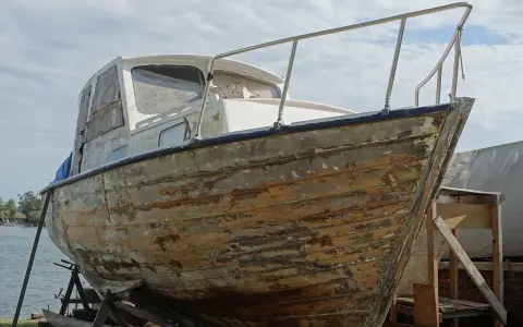 Bateau en bois sur cale, prêt à être restauré. Il faudra le nettoyer avant de naviguer sans antifouling.