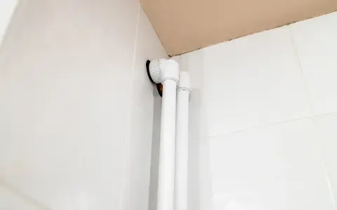Białe osłonki na rury co, zamontowane przy białych kafelkach, tworzą estetyczne wykończenie instalacji.