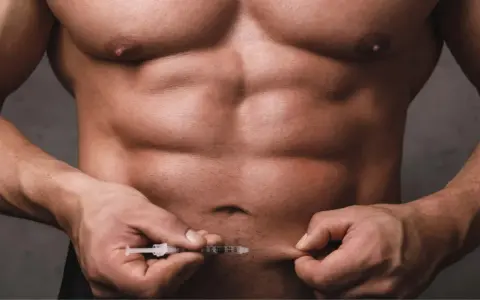 Ein Mann mit starker Muskulatur injiziert sich etwas in den Bauch. Dies könnte mit dem Thema Muskelaufbau Hormone zusammenhängen.