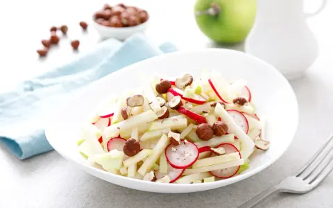 Frischer Kohlrabi Salat mit Radieschen und Haselnüssen, garniert mit Apfelstücken. Ein leichter Genuss!