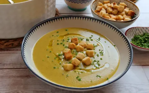 Un cremoso puré de verduras, adornado con picatostes crujientes y un chorrito de aceite de oliva.