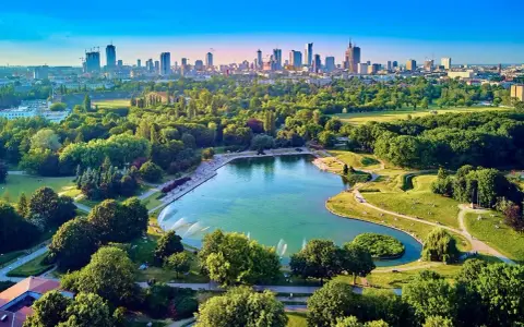 Piękny park z jeziorem i fontannami, idealne miejsce na relaks. W tle widać panoramę Warszawy, co czyni to jedno z fajnych miejsc w Warszawie.