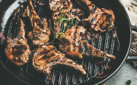Saftige Lammkoteletts mit Grillstreifen in einer Pfanne, garniert mit Rosmarin. Perfekt zum Lamm grillen!
