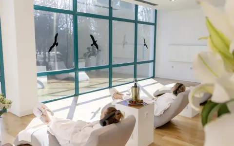 Relaks w spa, idealne **ciechocinek atrakcje na weekend**. Dwie kobiety w szlafrokach odpoczywają na leżakach, słuchając muzyki.