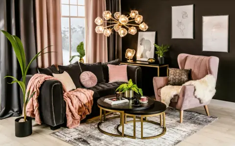 Elegancki salon z ciemnoszarą kanapą i różowym fotelem. Czy beżowy pasuje do czarnego? Tak, zwłaszcza gdy uzupełnione są różowymi akcentami.