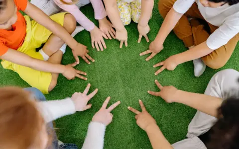 Dzieci tworzą krąg, pokazując palcami cyfry. To spokojne zabawy wyciszające Montessori, rozwijające koncentrację i współpracę.