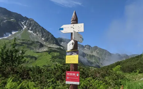 Droga do Morskiego Oka i Zawratu. W tle góry, a na pierwszym planie tabliczki szlaków. W oddali widać fragment szlaku na **Świstową Czubę**.