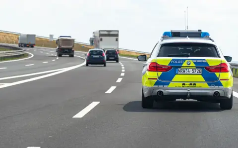 Niemiecka autostrada bez ograniczeń, gdzie policyjny radiowóz jedzie za innymi pojazdami.