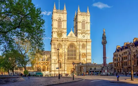 L'abbaye de Westminster, majestueuse et illuminée par le soleil, se dresse fièrement avec ses tours jumelles. Une colonne commémorative se dresse à droite.