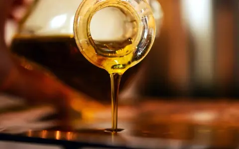 Olio d'oliva dorato cola da una bottiglia. Scopri come conservare l'olio di oliva per mantenerne intatto il sapore.