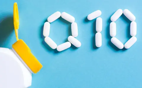 Białe kapsułki ułożone w kształt "Q10" obok otwartego pojemnika. Zastanawiasz się nad koenzym q10 – przeciwwskazania?