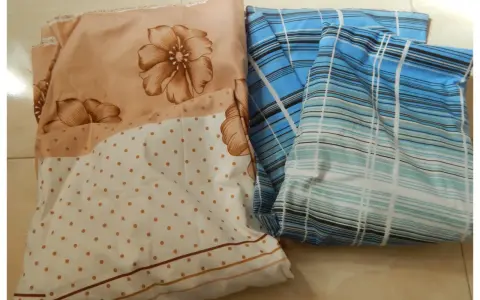 Tissus pliés, un à fleurs beiges et pois, l'autre à rayures bleues. Idéal pour apprendre comment faire un drap housse.