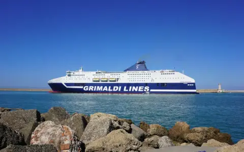Prom Grimaldi Lines wypływa z Livorno do Palermo. Statek "Cruise Sardegna" na tle błękitnego nieba i morza.