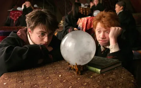 Harry i Ron wpatrują się w wirującą mgłę kryształowej kuli, która mówi, szukając odpowiedzi na lekcji wróżbiarstwa.