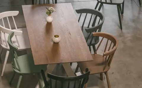 Holztisch mit bunten Stühlen und Deko-Elementen, aus der Vogelperspektive.