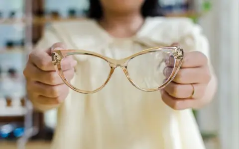 Osoba trzyma okulary korekcyjne, które pomagają widzieć wyraźniej.