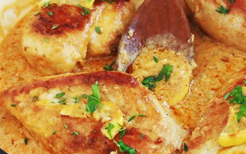 Un délicieux poulet à la crème, garni de persil frais et de rondelles de citron, mijote dans une sauce onctueuse.