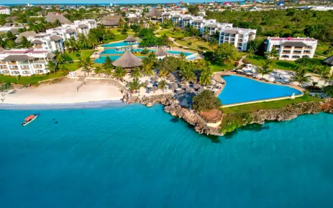 Widok z samolotu na tropikalny kurort na Zanzibarze z białymi budynkami, basenami i plażą nad turkusowym oceanem.