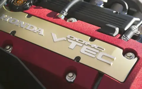 Złota pokrywa silnika Honda z napisem VTEC, otoczona czerwonym, błyszczącym wykończeniem.