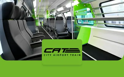 Wnętrze nowoczesnego pociągu CAT, czyli City Airport Train w Wiedniu. Jasne siedzenia i zielone akcenty tworzą przestronną atmosferę.