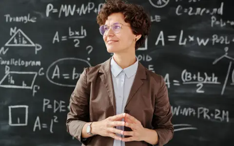 Lehrerin vor Tafel mit Matheformeln. Sie fragt sich, wie viel verdienen Grundschullehrer.