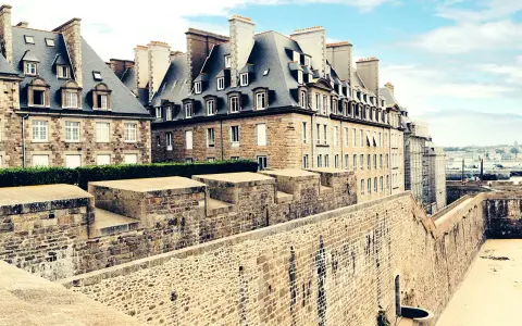 Murs de pierre de la ville fortifiée de Saint-Malo, avec des maisons bretonnes typiques et une vue sur la mer. Imaginez une pause à la taverne de Saint-Malo.