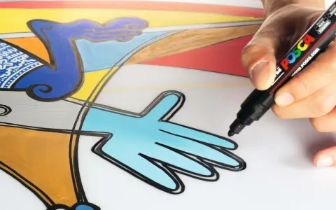 En hand använder en svart Posca-penna för att måla med posca pennor på en färgglad, abstrakt illustration.