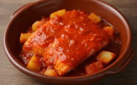 Bacalao a la riojana, un plato tradicional con trozos de patata y pimiento en una rica salsa de tomate.
