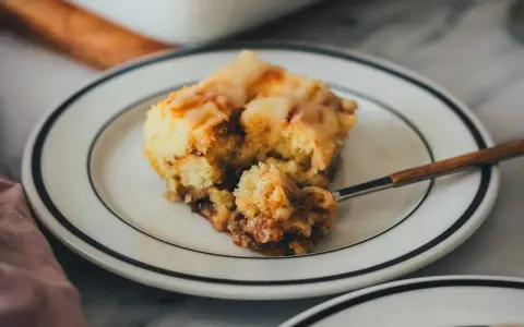 Ein Stück saftiger Zimtschneckenkuchen mit Zuckerguss, perfekt für ein Zimtschneckenkuchen Rezept.