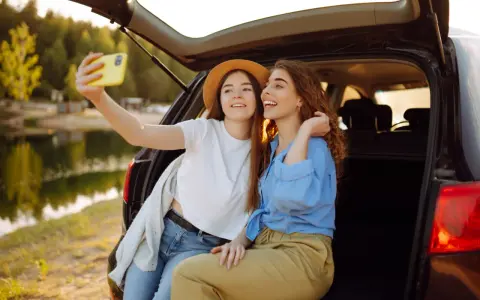 Dwie przyjaciółki robią sobie selfie nad jeziorem, ciesząc się wspólnym weekendem.