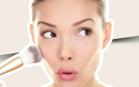 Una mujer aplica colorete en crema en sus mejillas con una brocha, creando un look natural y radiante.