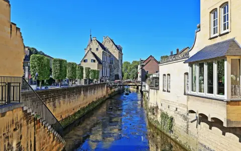 Idyllischer Kanal in der Valkenburg Altstadt, gesäumt von historischen Gebäuden und Bäumen.