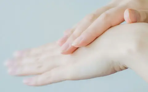 Två händer, en över den andra, med fokus på fingrarna. Huden ser torr ut, vilket kan tyda på eksem på fingrarna.