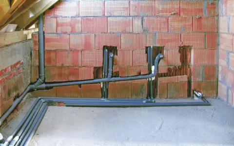 Instalacja hydrauliczna w trakcie budowy, widoczne rury kanalizacyjne i wodne. To kluczowy etap, by wiedzieć, jak zrobić odpowietrzenie WC.