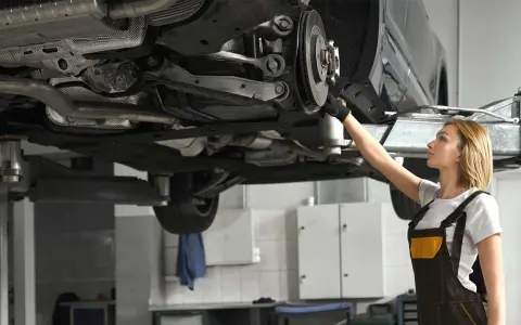 Mechaniczka sprawdza układ napędowy samochodu na podnośniku.