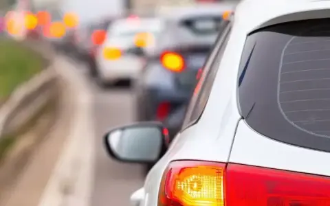 Un coche blanco en un atasco, con sus luces de freno rojas encendidas. ¿Cuántas luces de freno tiene un coche?