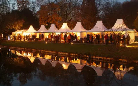 Festliche Zelte am havixbeck weihnachtsmarkt spiegeln sich im Wasser. Besucher bummeln durch die beleuchteten Stände.