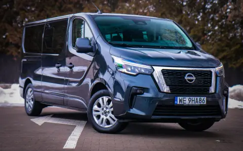 Ciemnoszary Nissan NV300 z nowoczesnymi światłami LED stoi na parkingu.