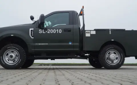 Ciemnozielony Ford F350 z zabudową typu "flatbed" i numerem SL-20010. Solidna maszyna gotowa do pracy.