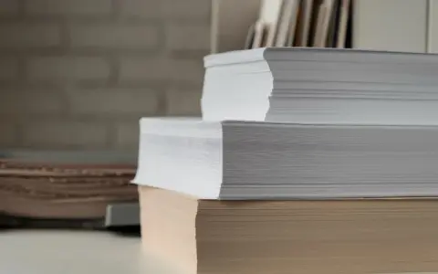 Stosy białego i beżowego papieru, gotowe do druku. Ten papier powlekany czeka na kreatywne projekty.