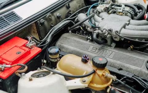 Silnik BMW 1.6 mpi z widocznym akumulatorem i zbiorniczkiem płynu.